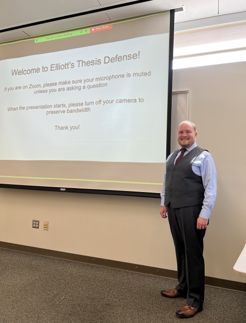 Elliott standing next to projector screen